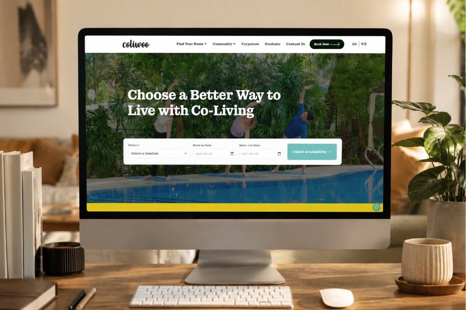 Desktop monitor on a wooden desk displaying a co-living website with a pool backdrop and the headline 'Choose a Better Way to Live with Co-Living'