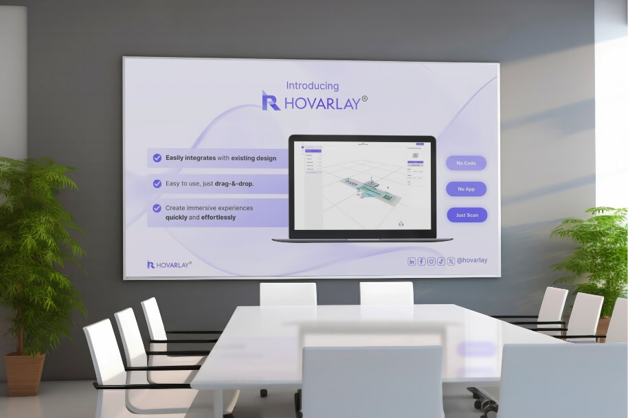 Modern conference room with a large HOVARLAY promotional banner on the wall, a long white table, white chairs, and potted plants nearby.