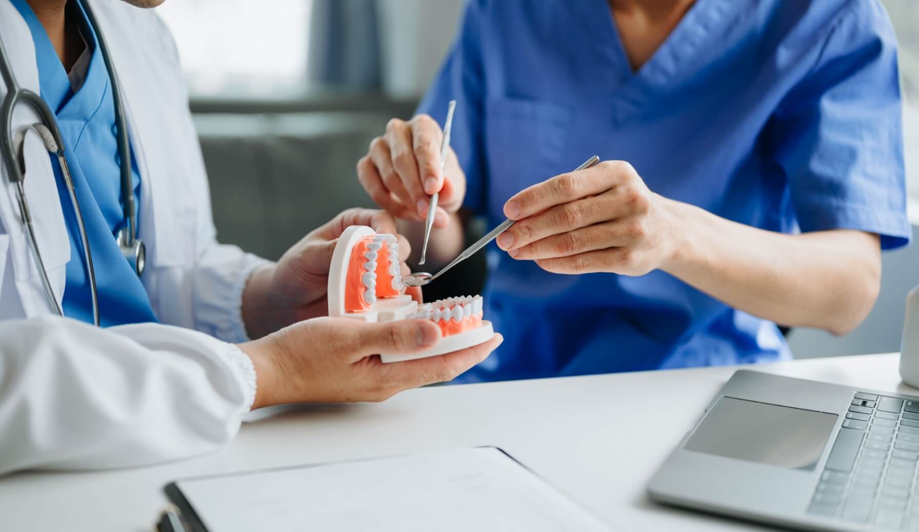 Dentists demonstrate dental model with tools on a table, showing brushing technique for patient education