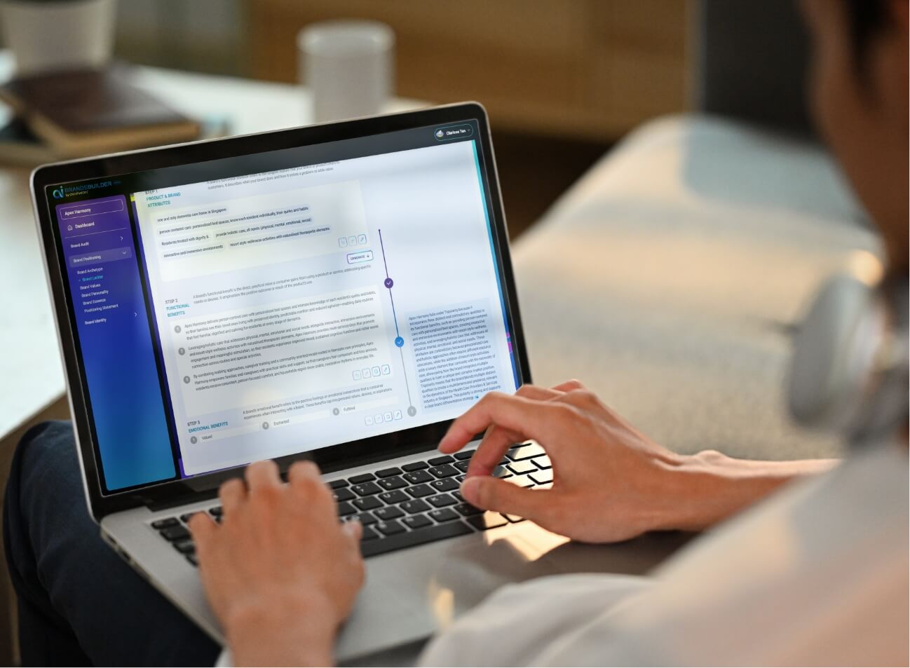 Person typing on a laptop displaying a software interface with a vertical blue sidebar and a chart/diagram on the screen in a cozy workspace.